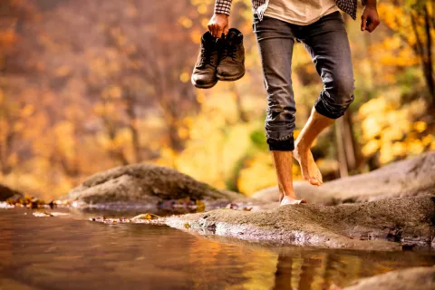 Hombre caminando descalzo por la orilla de un río