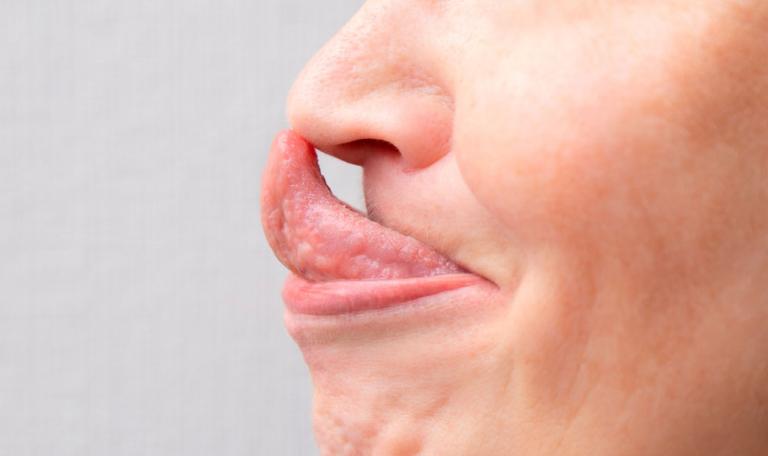 Mujer tocando su nariz con la punta de la lengua
