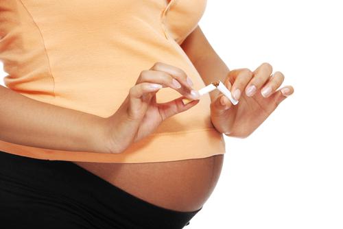 Mujer embarazada rompiendo un cigarrillo
