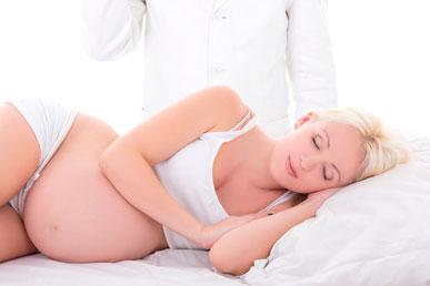 Mujer embarazada tumbada en la cama