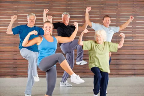 Personas mayores hacen gimnasia con su monitora