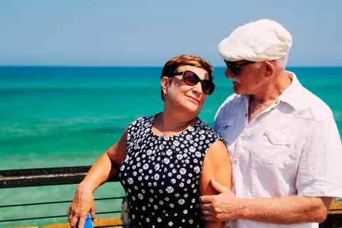 Una pareja de adultos mayores pasea junto al mar