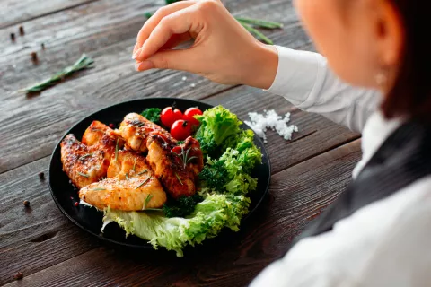 Una mujer añade pimienta a su plato de comida