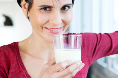 Una mujer sostiene un vaso con leche de soja