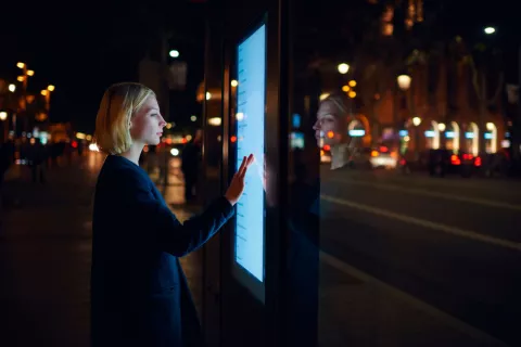 Una mujer consulta un panel interactivo en una ciudad inteligente