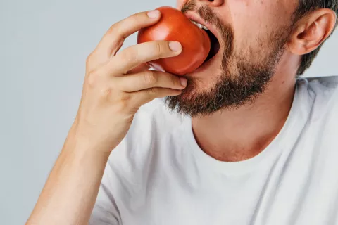 Hombre mordiendo un tomate