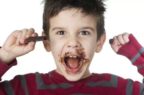 Niño excitado comiendo mucho chocolate