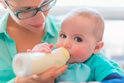 Una madre alimenta a su hijo con un biberón