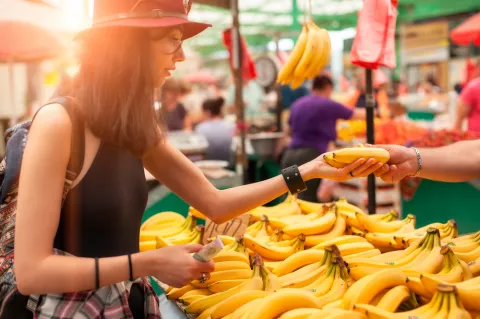 Una mujer compra plátanos en un puesto del mercado