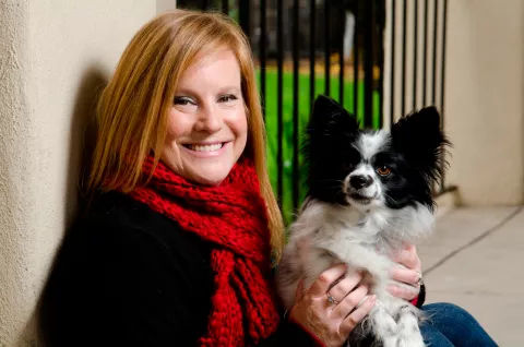 Una mujer posa sonriente con su perro papillon en brazos