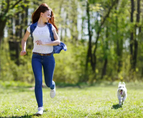 Una mujer corre junto a su cachorro por un parque