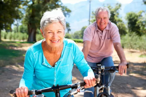 Una pareja de mayores monta en bicicleta por el campo