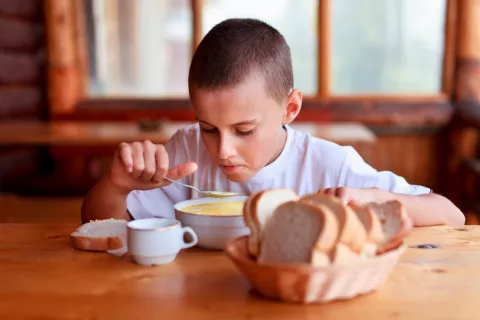 Niño con cáncer con mucositis intentando comer