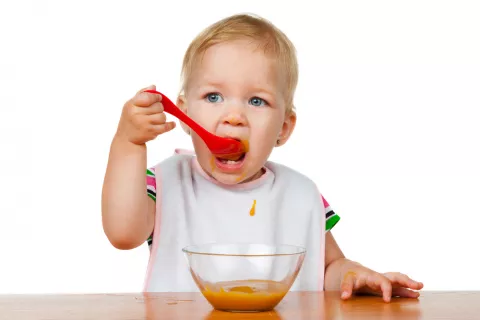 Niño con un añito comiendo solo