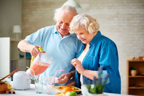 Pareja de adultos mayores se dispone a tomar un zumo de frutas preparado por ellos