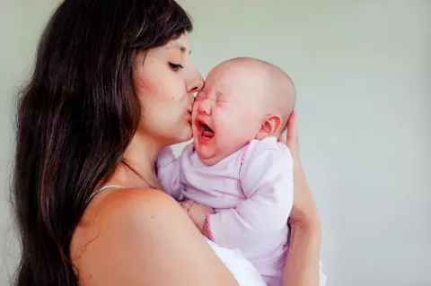 Madre coge en brazos a bebé que llora