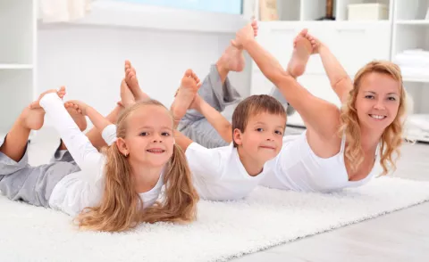 Mujer practicando yoga con sus hijos