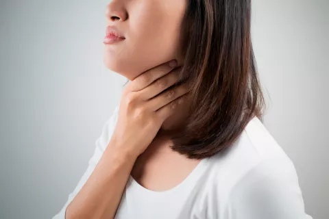 Una mujer se palpa el cuello