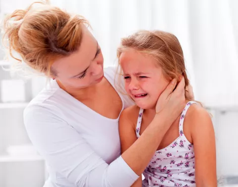 Niña con signos de mamitis llorando en brazos de su madre