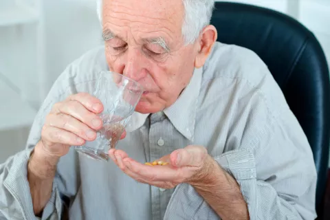 Persona mayor tomando pastillas para la demencia