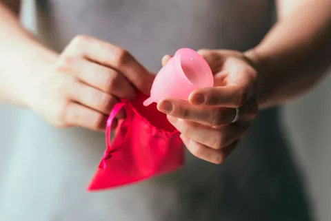 Mujer extrae una copa menstrual de la bolsa donde se guarda