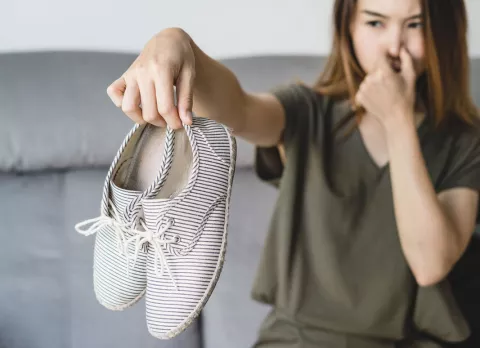 Mujer sujetando unas botas que desprenden mal olor