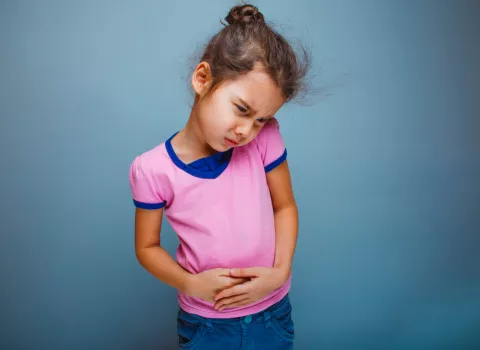 Niña pequeña se toca la barriga con gesto de dolor