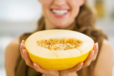 Mujer sujetando un melón amarillo