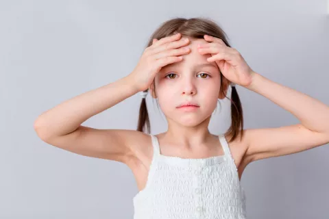 Una niña pálida se toca la frente