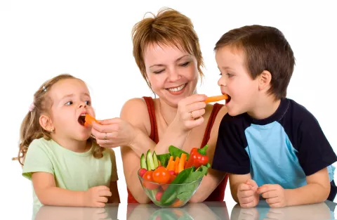 Una madre da verduras a sus hijos pequeños