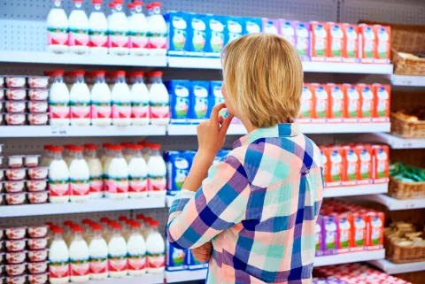 Mujer indecisa para comprar leche y lácteos