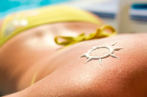 Espalda de una mujer con el dibujo de un sol hecho con crema protectora