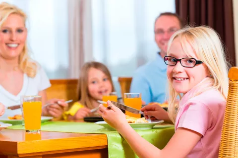 Familia enseñando a sus hijos buenos modales en la mesa