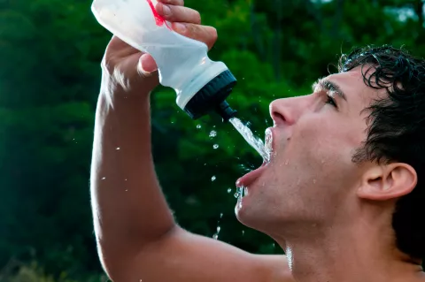 Hombre bebiendo de una botella al aire libre