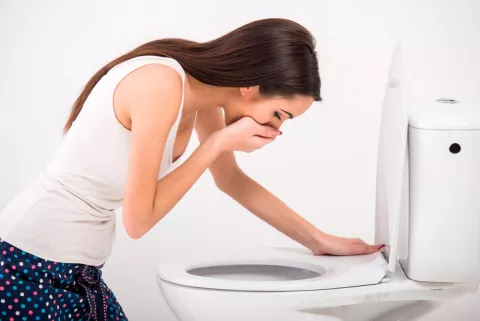 Mujer a punto de vomitar en el baño