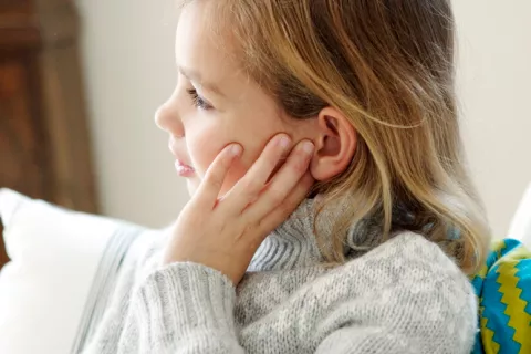 Niña se toca el oído dolorido