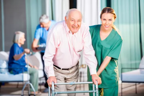 Una cuidadora ayuda a un anciano en una residencia