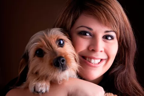 Una mujer posa sonriente con su perro en brazos