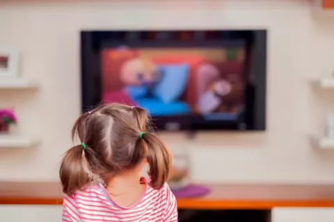 Niño pequeño junto a un televisor