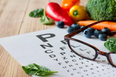 Unas gafas junto a un grupo de verduras ricas en luteína