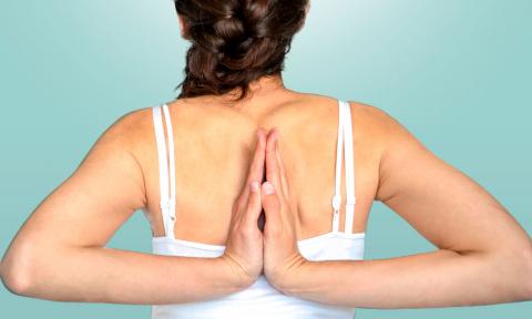 Mujer flexionando los codos hacia la espalda hasta juntar sus manos