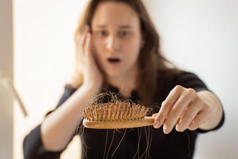 Mujer mirando asombrada el cepillo del pelo lleno de cabello