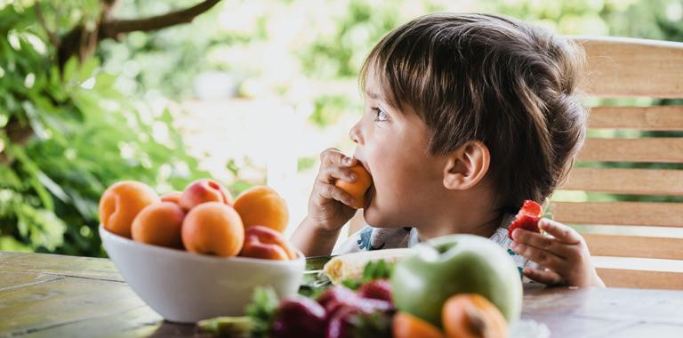 Niño comiendo fruta al aire libre