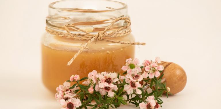 Flores de manuka junto a tarro con miel