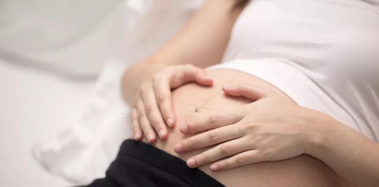 Embarazada apoya las manos en su vientre Embarazada recostada con las manos sobre el vientre