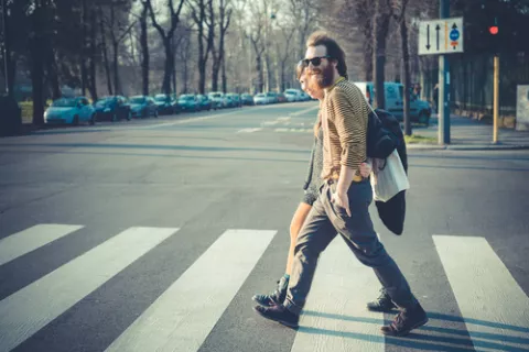 Pareja caminando por la ciudad cruzando un paso de cebra