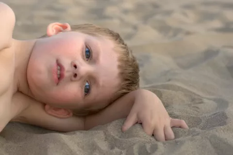 Niño autista tumbado en la playa