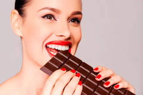 Mujer mordiendo una tableta de chocolate