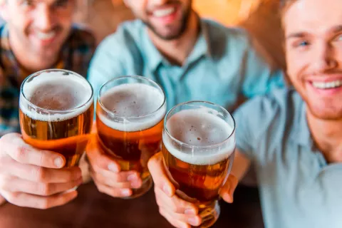 Hombres sostienen jarras de cerveza