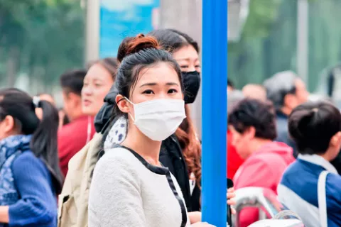 Mujer camina por la calle con una mascarilla